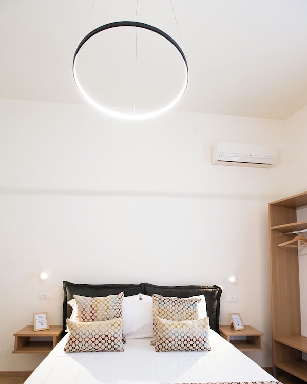 A bedroom with a bed, bedside tables, a wardrobe, and an air conditioning unit.