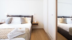 Una habitación de hotel con una cama, una mesita de noche, un espejo y suelo de madera.