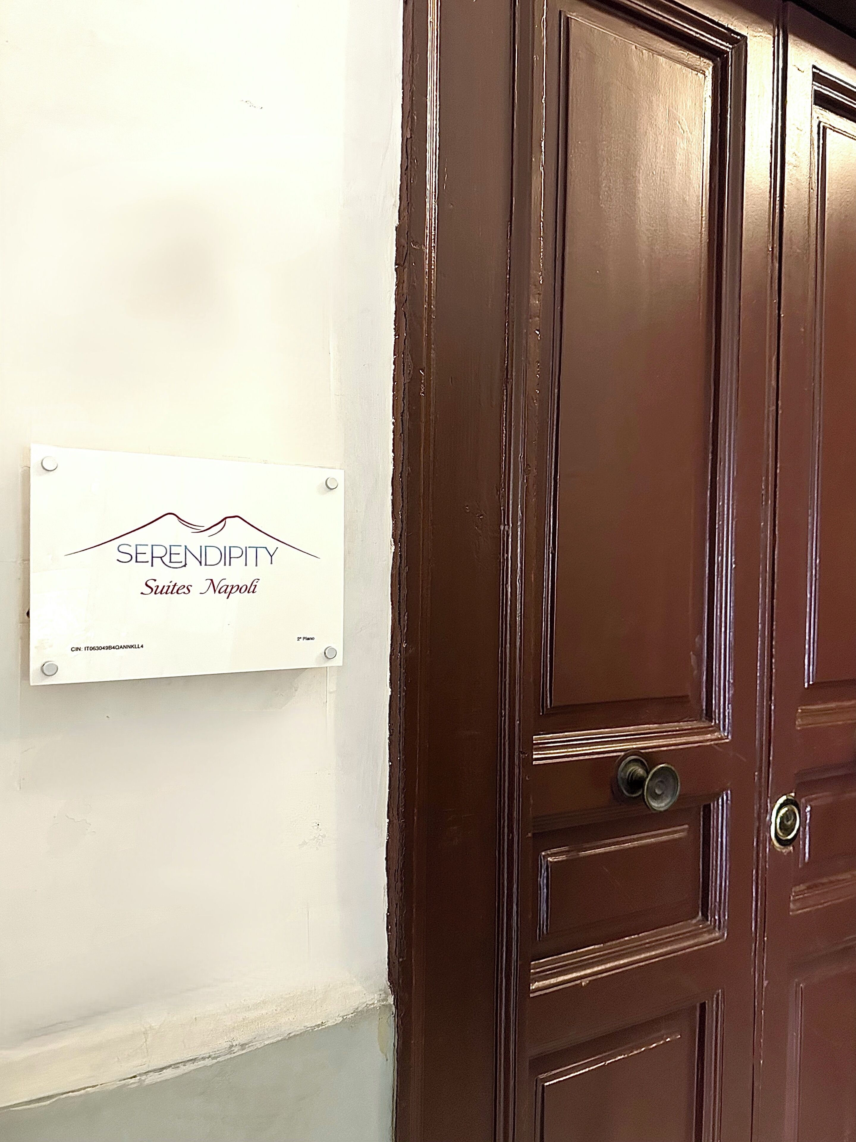 A brown door with a sign on the wall to the left.
