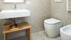 Un baño moderno con lavamanos, espejo y retrete blancos.