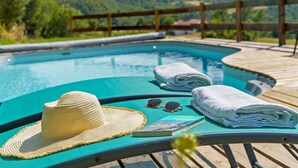 Ein Poolbereich mit Liegestuhl, Strohhut, Sonnenbrille und Handtüchern.