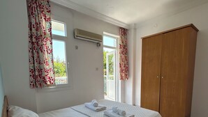A bedroom with a bed, a wardrobe, a bedside table with a remote control, and an air conditioning unit. - double comfort marmaris (muğla)