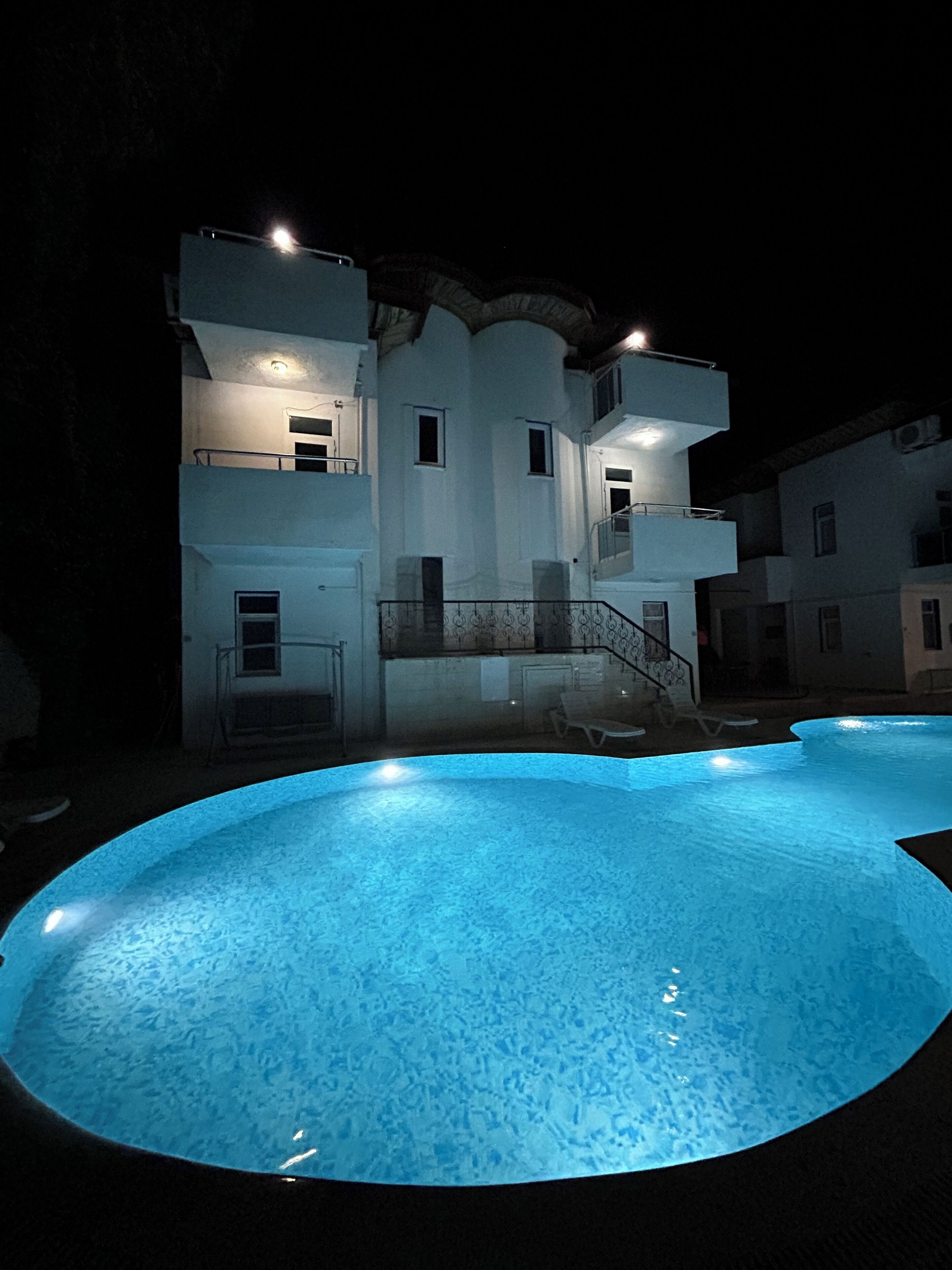 A multi-story building with a swimming pool at the front.