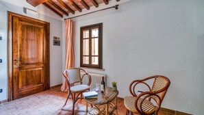 A room with a wooden door, a window with shutters, wicker chairs, a small table with a book and a glass, and a radiator. - A charming 65 sqm apartment, ideal for four people, located on the first floor of a building without an elevator.The apartment is located in a charming Umbrian-style farmhouse, with ample green space, relaxation areas, and a shared swimming pool. Its loc (San Martino In Campo)