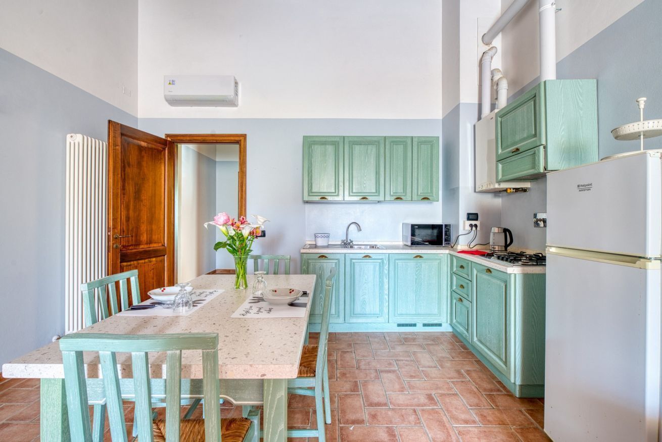 A kitchen with teal cabinets, a white refrigerator, a microwave, and a stove.