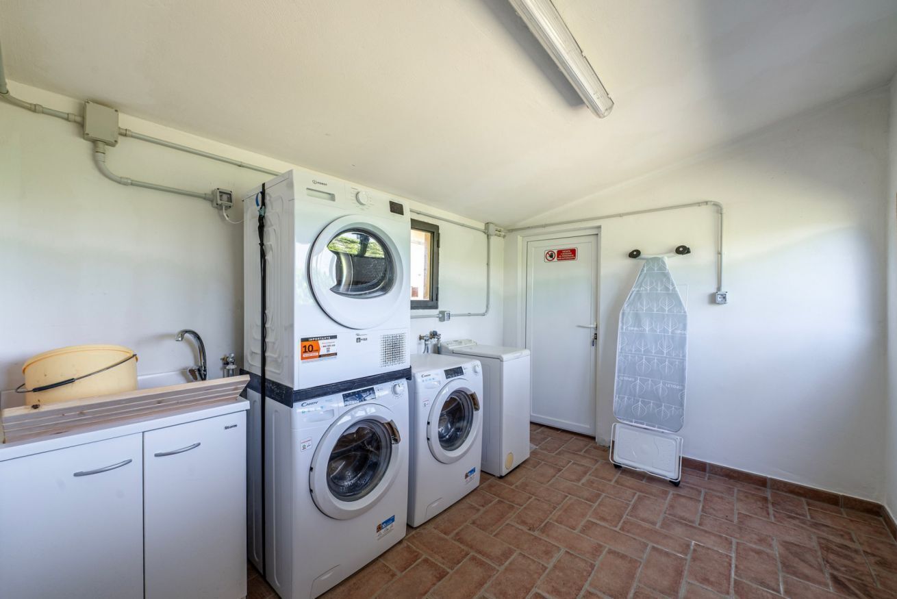 A laundry room with two washing machines, a drying rack, and a sink.