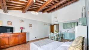 A bedroom with a bed, wooden headboard, a dresser, a television, and a kitchen area with cabinets and a refrigerator. - A charming 65 sqm apartment, ideal for four people, located on the first floor of a building without an elevator.The apartment is located in a charming Umbrian-style farmhouse, with ample green space, relaxation areas, and a shared swimming pool. Its loc (San Martino In Campo)