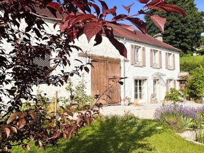 Ein weißes Gebäude mit rotem Ziegeldach, einer Holztür und einem Fenster mit Fensterläden.