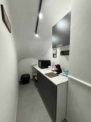 A compact kitchen with a microwave, sink, and cabinets. - Centurioni Tourist Accommodation (Civitavecchia)
