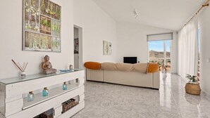 Un soggiorno moderno con un divano, un tavolino in vetro, una TV e vista sull'esterno.