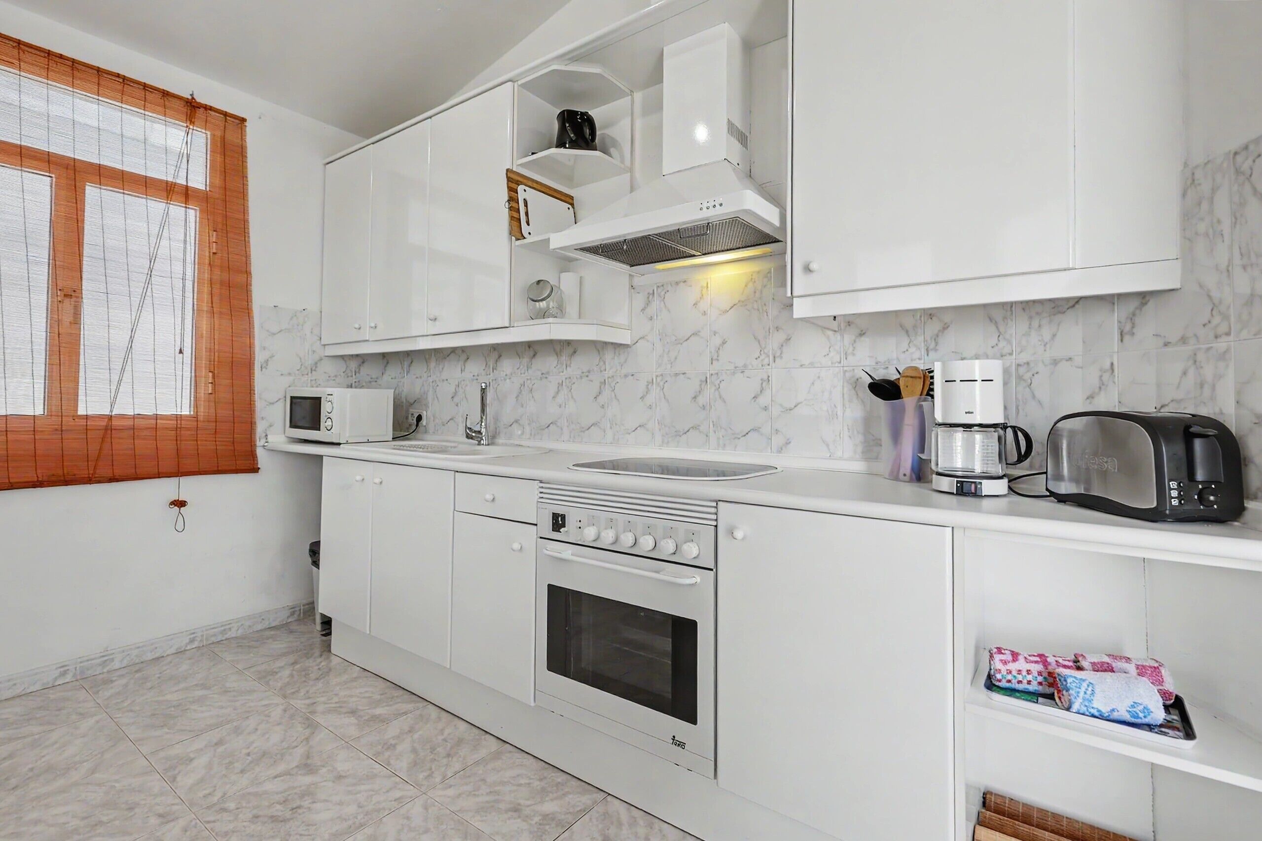 A modern kitchen with white cabinets, a built-in oven, a microwave, and a toaster.