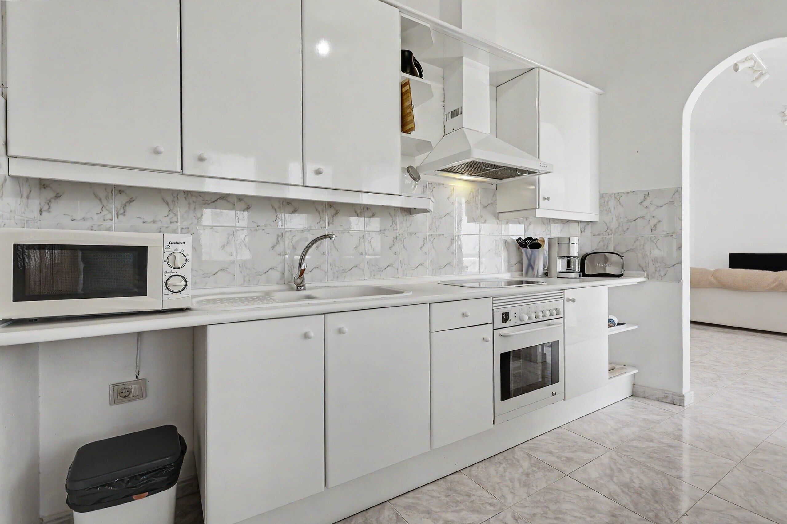 Una cocina moderna con armarios blancos, microondas, fregadero y horno.