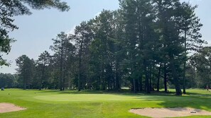 A golf course with sand bunkers, trees, and a clear sky. - Cozy Bear Cabin / Trails, Firepit & Northern MI (Kalkaska)