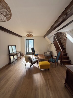 Ein geräumiges Wohnzimmer mit Holzboden, einer Steintreppe und einem großen Fenster, das natürliches Licht hereinlässt.