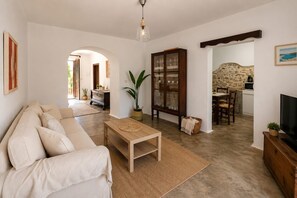 Ein Wohnzimmer mit einer Couch, einem Holztisch, einer Vitrine mit Glastüren, einem Fernseher und einer Steinwand.