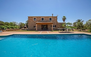 Ein zweistöckiges Steinhaus mit einem Pool davor.