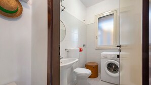 A compact bathroom with a toilet, sink, and washing machine. - Apartment 'Villetta Sea Sun' with Shared Pool, Private Terrace, and Air Conditioning (Eurovillage)