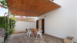An outdoor patio with a table and chairs, a bamboo canopy, and a potted plant. - Apartment 'Villetta Sea Sun' with Shared Pool, Private Terrace, and Air Conditioning (Eurovillage)