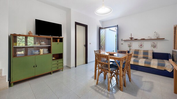 A living room with a dining table, chairs, a television, and a sofa. - Apartment 'Villetta Sea Sun' with Shared Pool, Private Terrace, and Air Conditioning (Eurovillage)