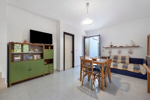 A living room with a dining table, chairs, a television, and a sofa.