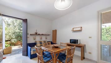 A modern living space with a dining area, a sofa, and a TV.