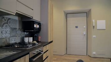 A modern kitchen with a gas stove, oven, and microwave, wooden cabinets, and a tiled backsplash.