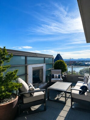 Una terrazza sul tetto con posti a sedere all'aperto, un caminetto e vista sulla città e sulle montagne.