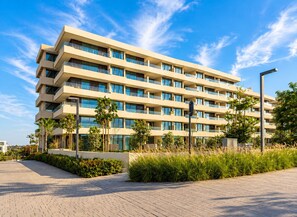 Et moderne hotel med flere etager, altaner, en anlagt sti og grøn bevoksning omkring.