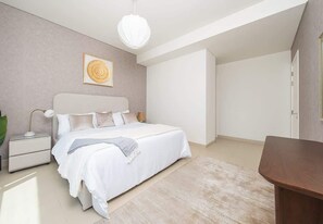 Quarto com cama, mesas de cabeceira, luminária pendente e uma porta.