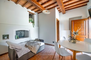 A bedroom with a bed, a small table with chairs, a window with a view, and a wooden ceiling. - GuestHost - Il Casale dei Gelsi - Narciso (San Martino In Campo)