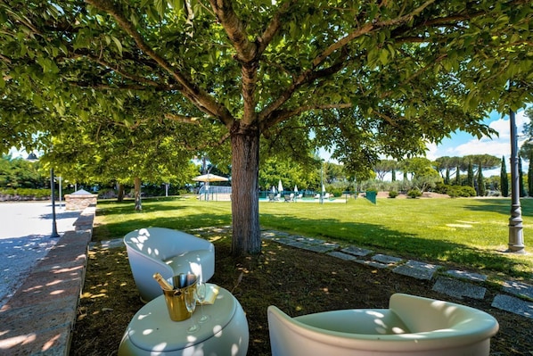A tree-lined outdoor seating area with a stone pathway and a view of a park. - GuestHost - Il Casale dei Gelsi - Narciso (San Martino In Campo)