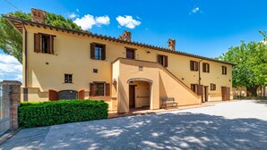 A two-story building with a beige facade, multiple windows, and a small entrance with a bench. - GuestHost - Il Casale dei Gelsi - Narciso (San Martino In Campo)