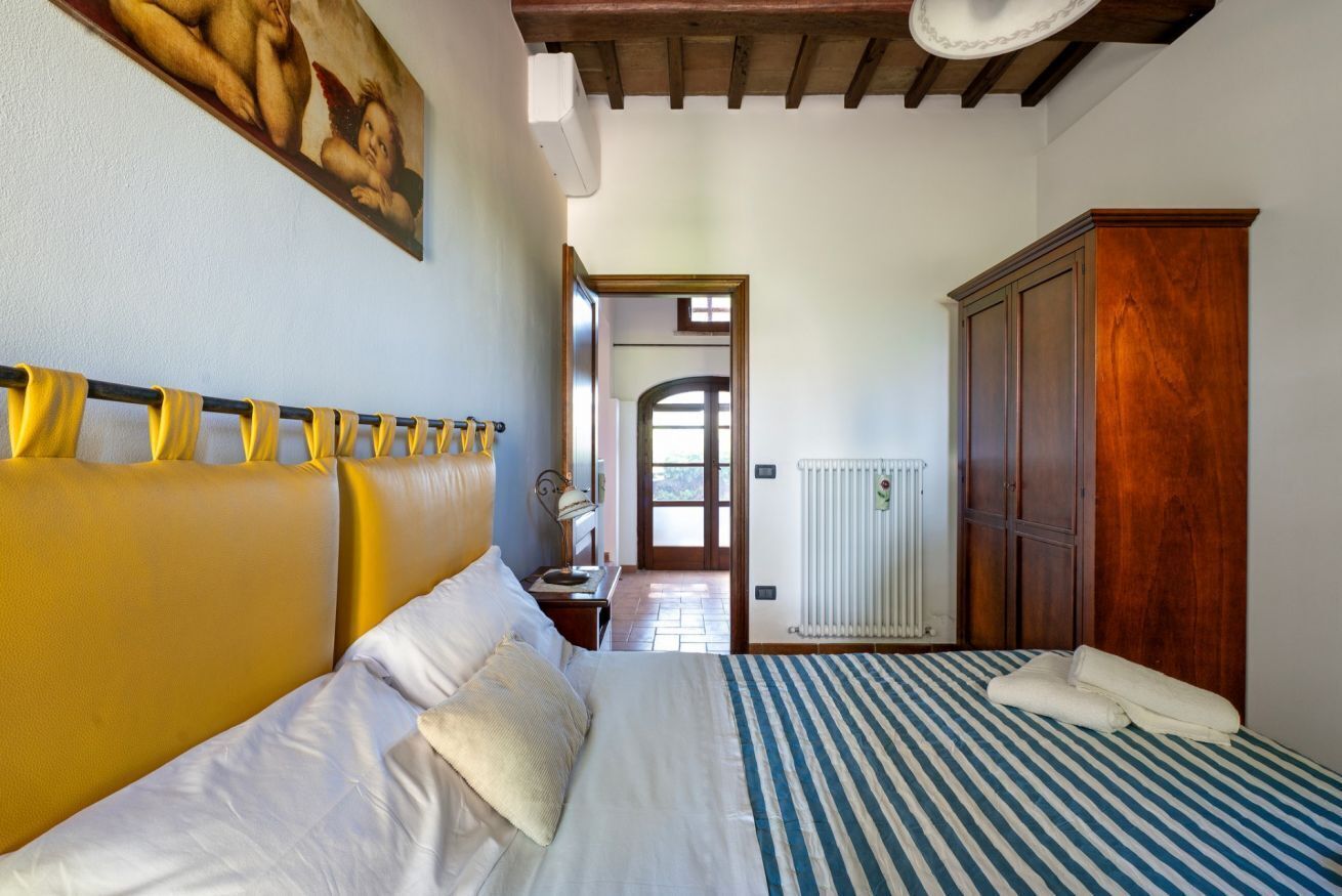 Een slaapkamer met een bed, een kledingkast, een radiator en een deur naar een andere kamer.