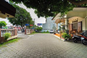 A paved entrance with a gate, a building with a sign, and parked motorcycles. - Griya Sastrowardoyo by ARBA (Yogyakarta)