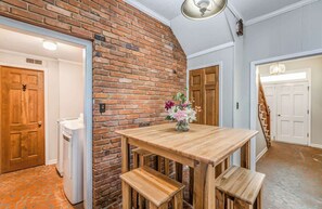 Ein Zimmer mit Backsteinwand, Holztür und einem Tisch mit Bänken.