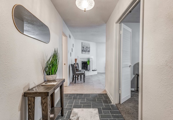 A hallway with a mirror, a potted plant, a table with a notebook, a fireplace, and a dining area. - Near Dining, Shopping, Parks! Tranquil Fox Trails (Memphis)