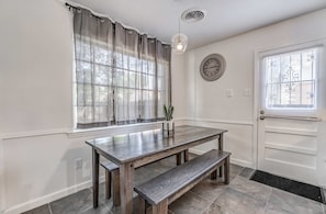 A dining area with a wooden table and bench, a potted plant, a clock, and a window with curtains. - Near Dining, Shopping, Parks! Tranquil Fox Trails (Memphis)