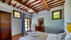 A bedroom with a bed, wooden wardrobe, dresser, and a window with a view of greenery. - GuestHost - Il Casale dei Gelsi - Tulipano (San Martino In Campo)