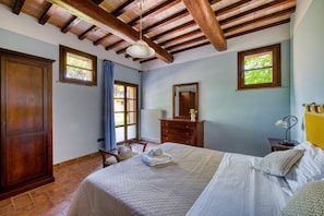 A bedroom with a bed, wooden wardrobe, dresser, and a window with a view of greenery. - GuestHost - Il Casale dei Gelsi - Tulipano (San Martino In Campo)