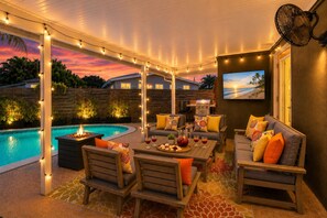 An outdoor patio with a pool, seating, and string lights. - Private Oasis Near Beach - Heated Pool, Lounge, Bikes (Pompano Beach)