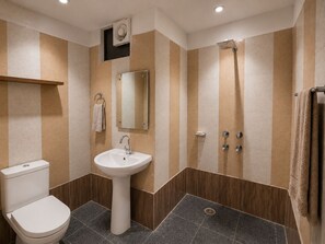 Un baño moderno con inodoro, lavabo, espejo y ducha.