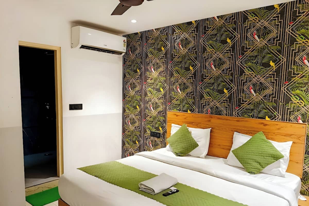 A bedroom with a wooden headboard, a green bedspread, and a patterned wallpaper.