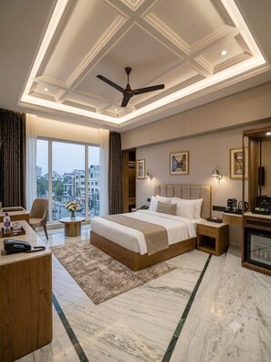 A modern hotel room with a large bed, a desk, a chair, a coffee machine, and a view of the city. - Hotel Star City (New Delhi)