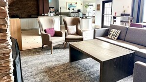 A modern hotel lobby with a seating area, a kitchen in the background, and a stone accent wall. - Studio Suite with River Views | Free Breakfast (Great Falls)