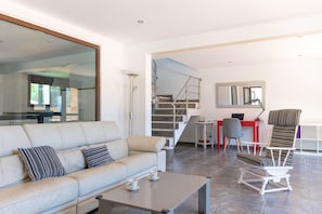 Ein modernes Wohnzimmer mit einer Couch, einem Couchtisch und einem Sessel. Eine Treppe führt zu einer weiteren Ebene.