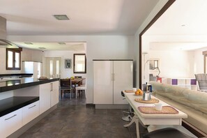 Cozinha moderna com área de jantar, sofá e vista para a sala de estar.