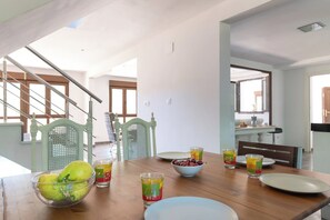 Un comedor con una mesa de madera, sillas y un bol de fruta.
