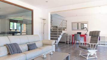 Una sala moderna con sofá, mesa de centro y comedor con una mesa y sillas rojas.
