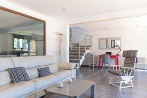Uma sala de estar moderna com sofá, mesa de centro e área de jantar com mesa e cadeiras vermelhas.