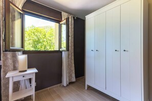 A room with a window, a wardrobe, and a bedside table.